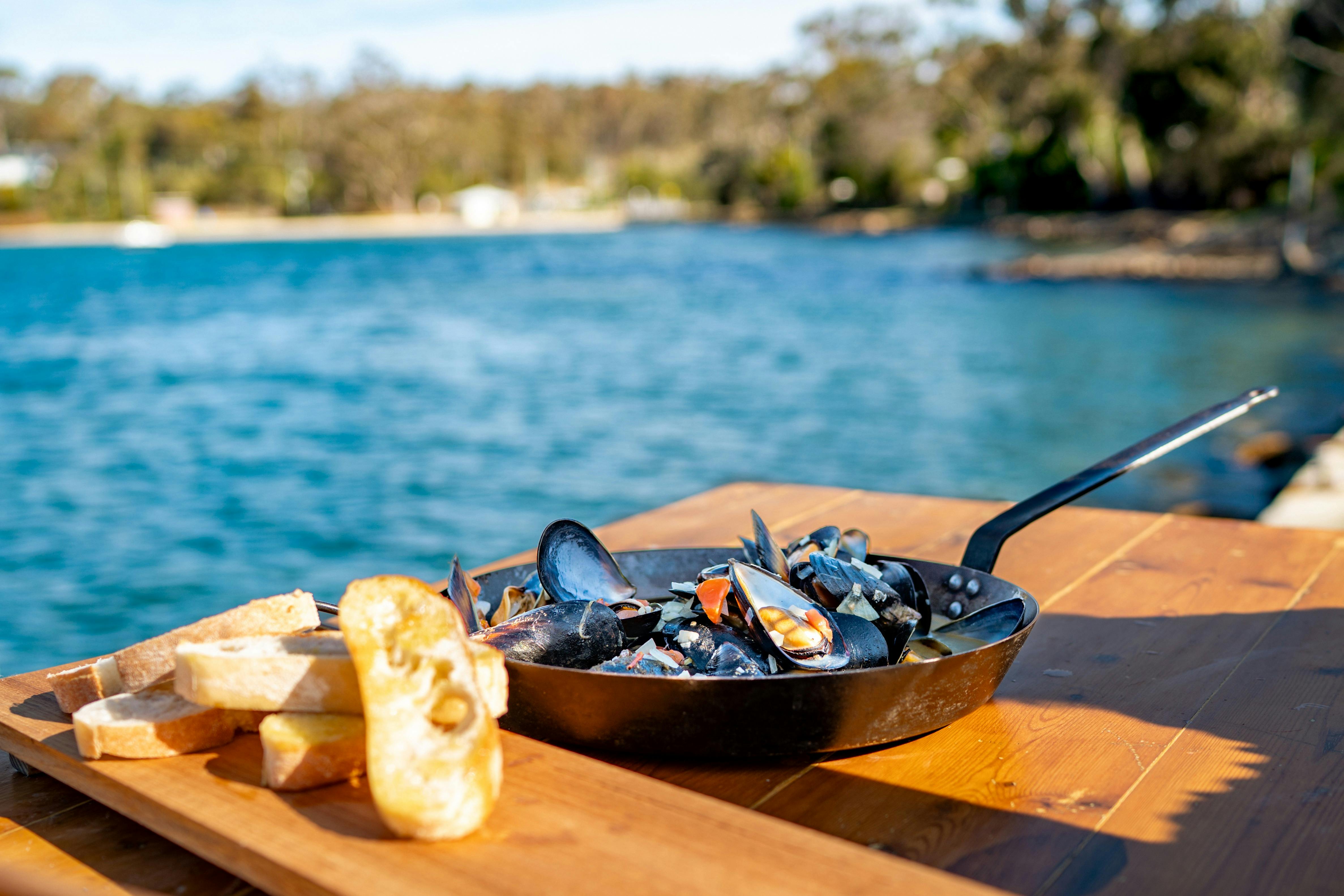 Pan of fresh mussles being served by the seaside on a sunny afternoon