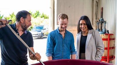 A couple in a Canberra winery looking at fermenting red grapes