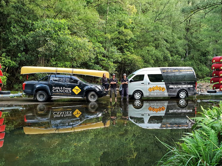 two vehicle with canoes reflecting in the water