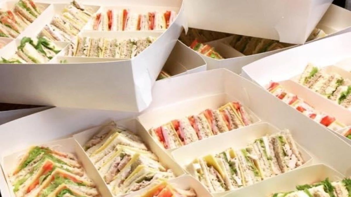 Boxes filled with mixed sandwiches cut into quarters