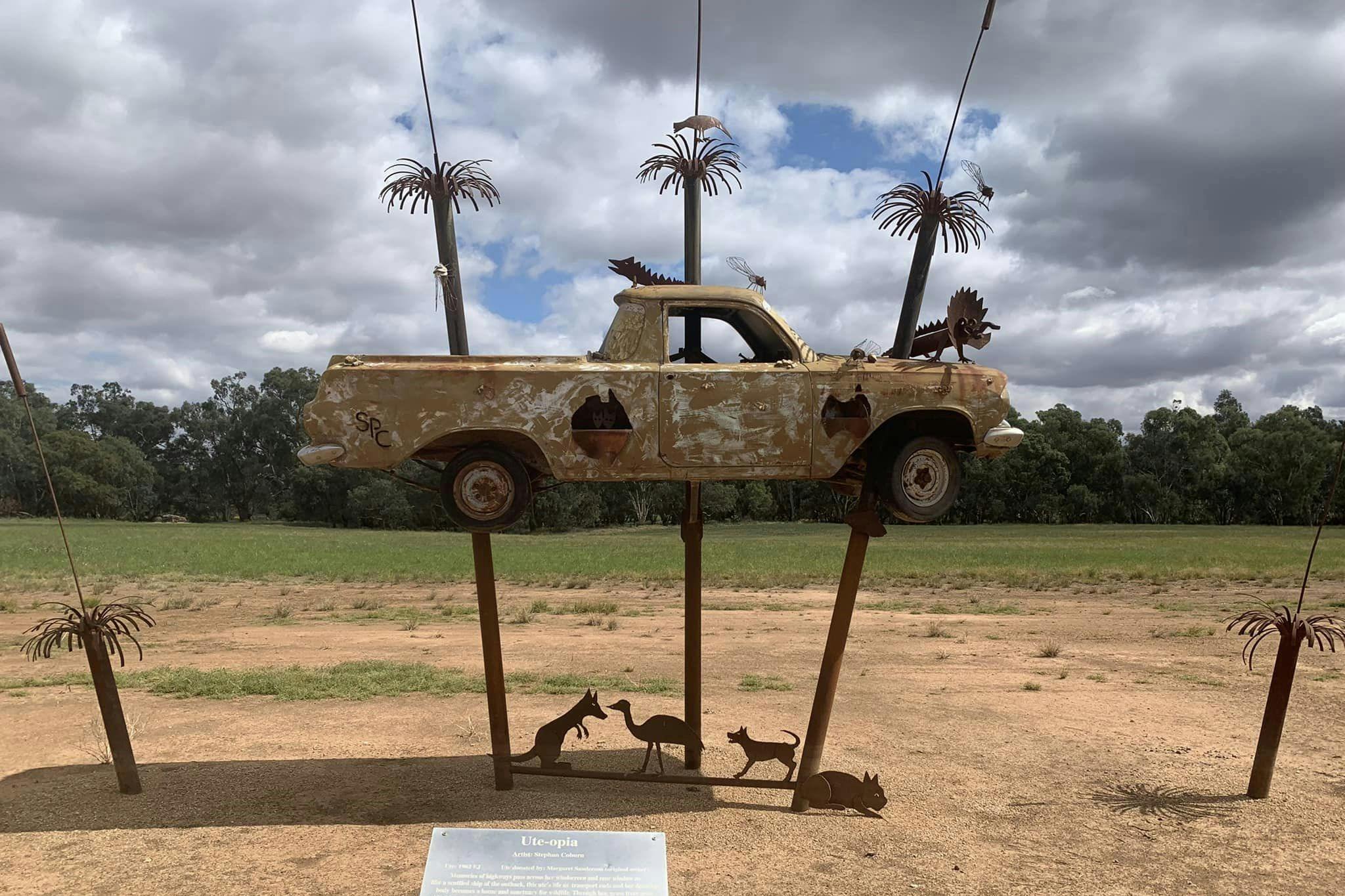 A sculpture of a ute on 2 poles that look like palm trees