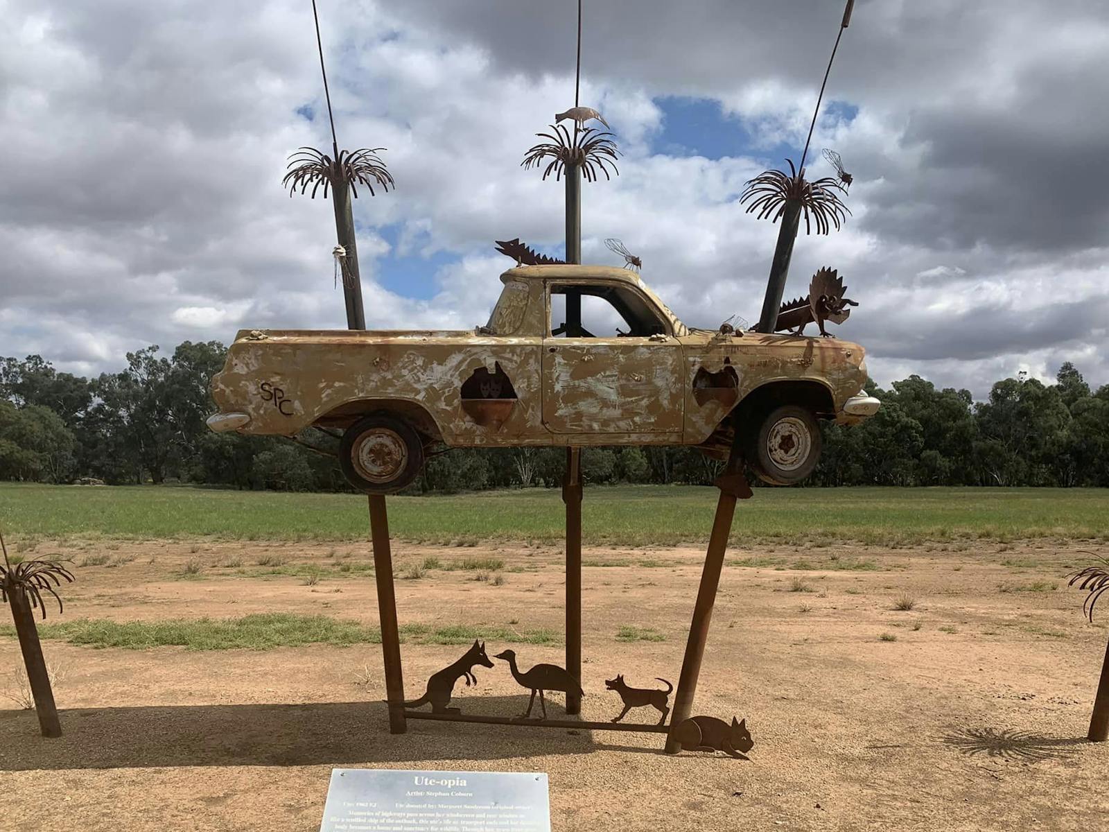 A sculpture of a ute on 2 poles that look like palm trees