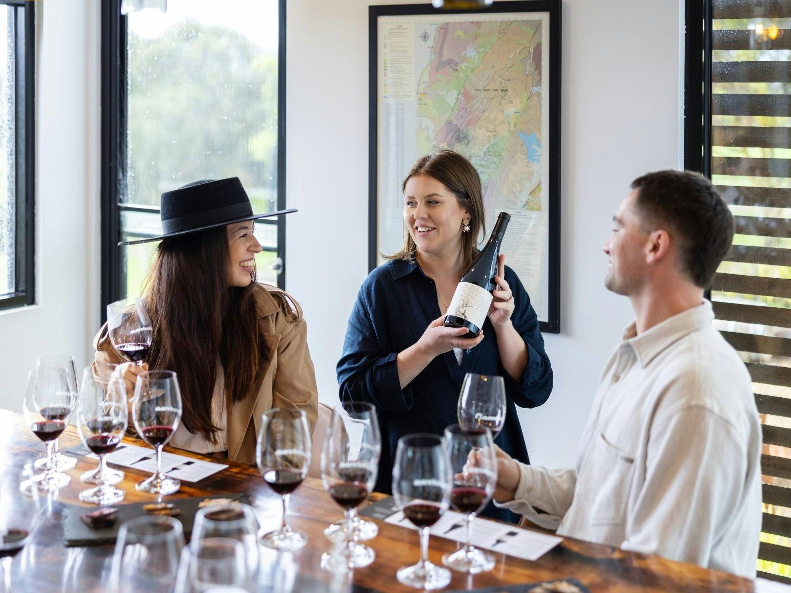 Group sitting at table for wine tasting experience at Gemtree Wines. Host talking about a bottle.