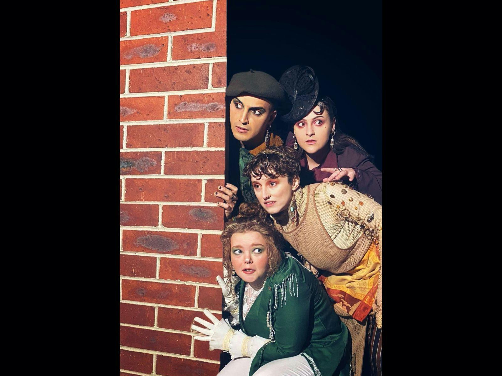 Four people looking around a wall