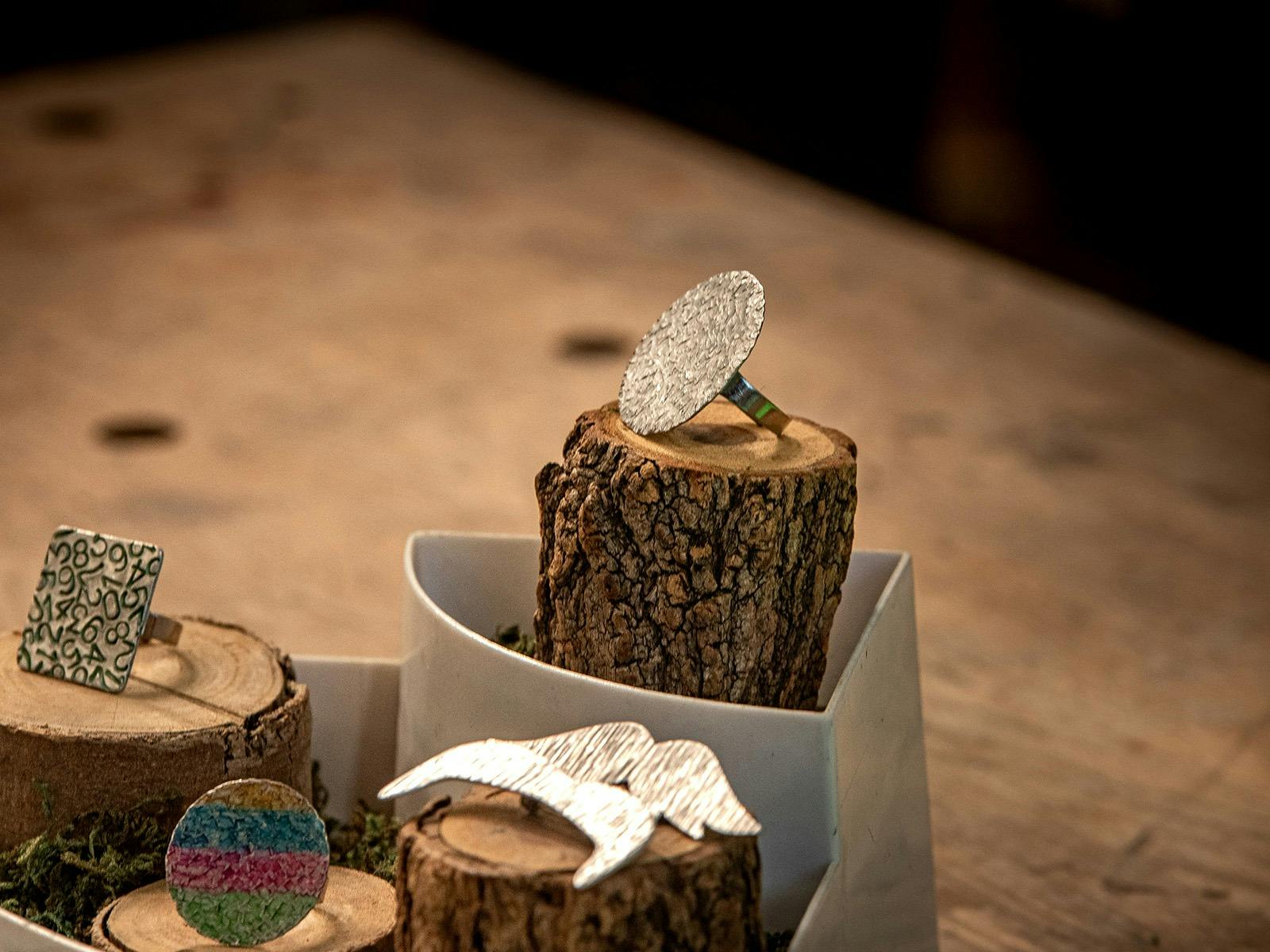 4 handforged rings of different colours, sizes and styles displayed on natural wood stands. 4 handforged rings of different colours, sizes and styles displayed on natural wood stands.