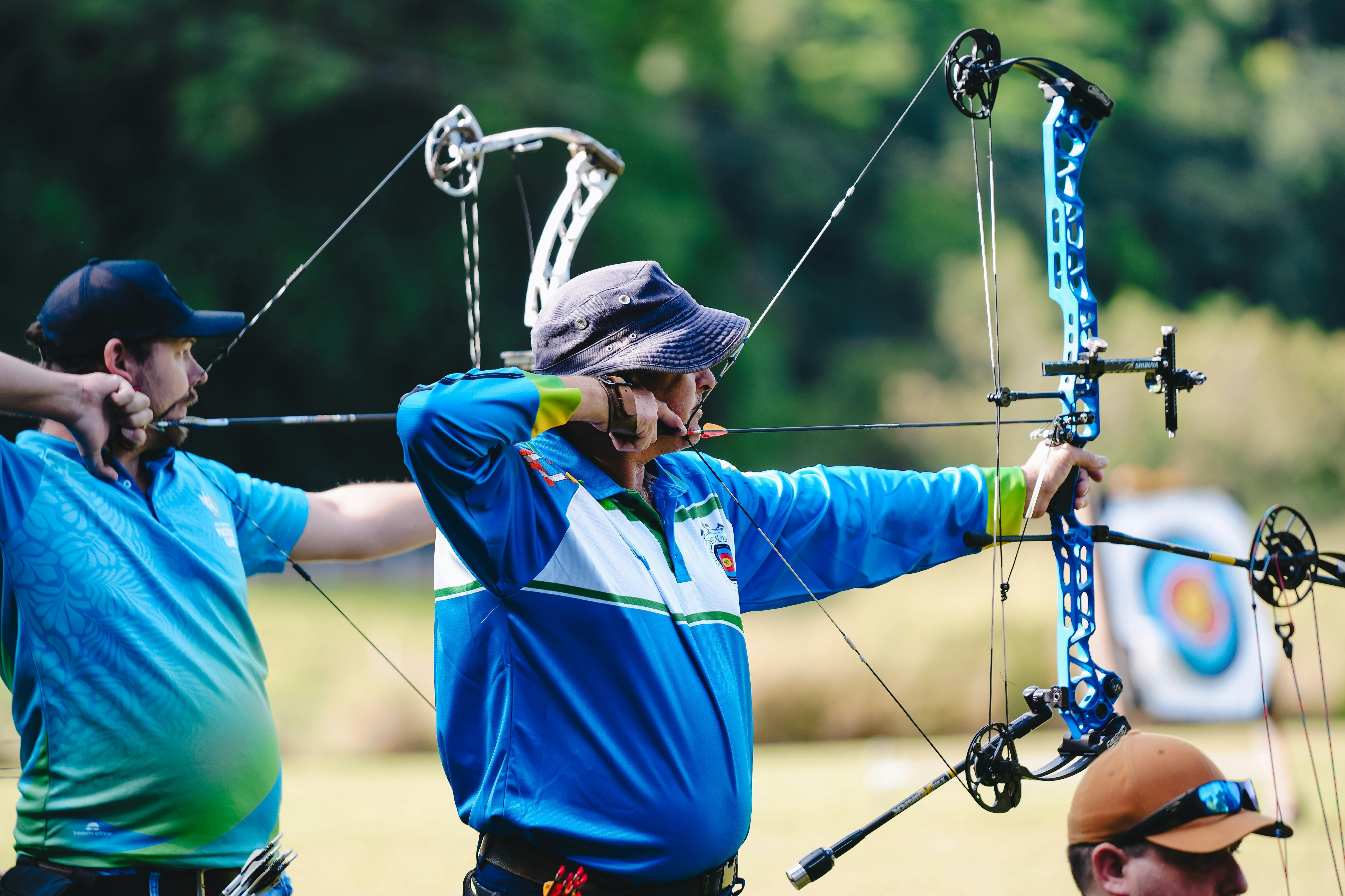 Two archers focus  while drawing their bows at an outdoor shooting range