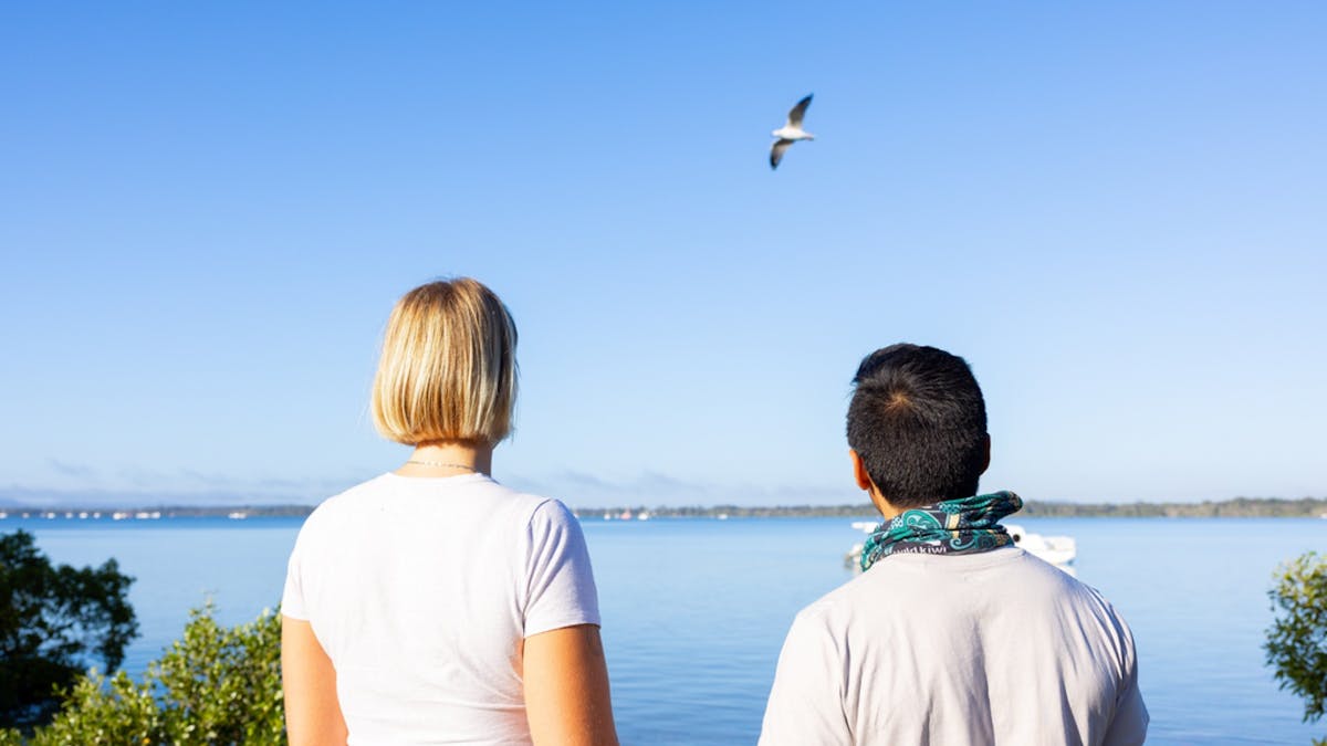 A couple looking up at the sky at a bird at Tin Can Bay