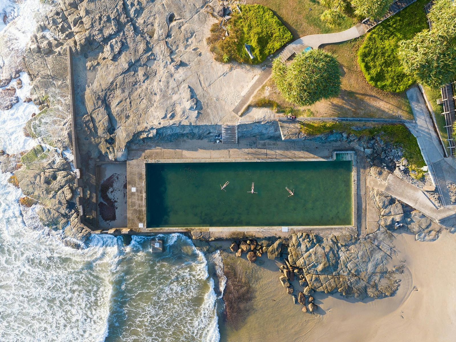 Yamba Main Beach and Ocean Pool with three swimmers floating