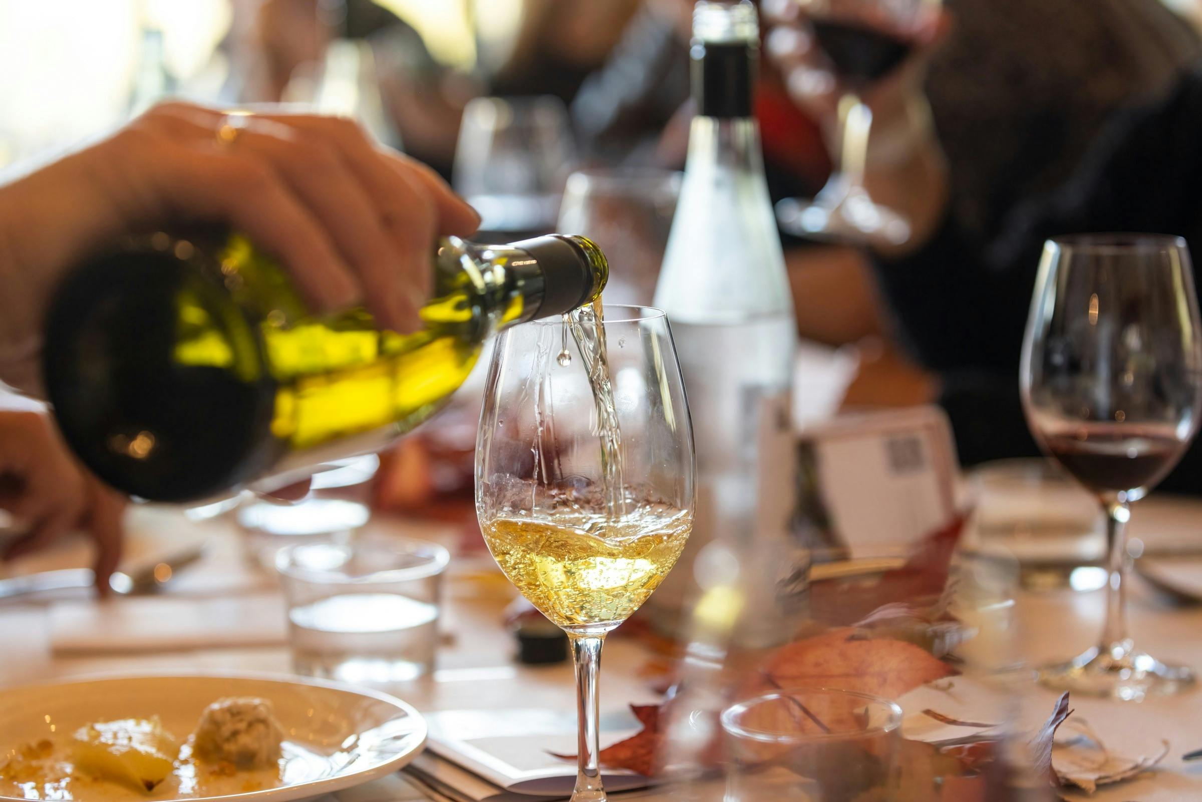 A hand is pouring a glass of chardonnay