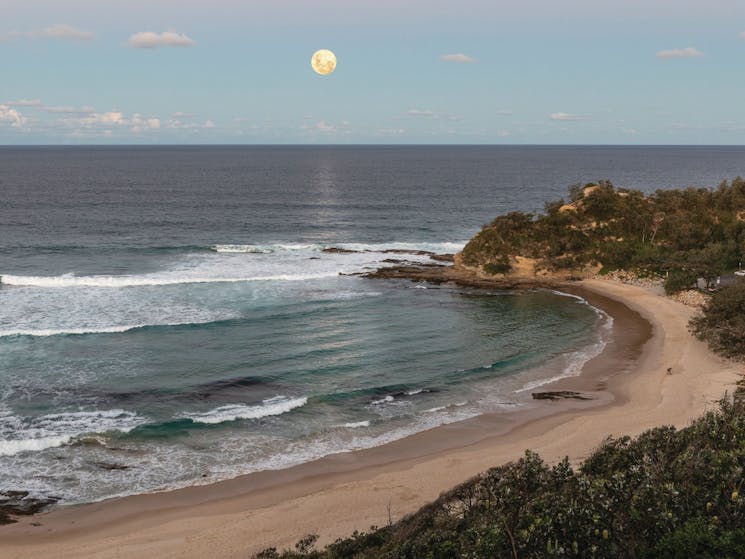 Full moon is rising over the ocean as evening comes in