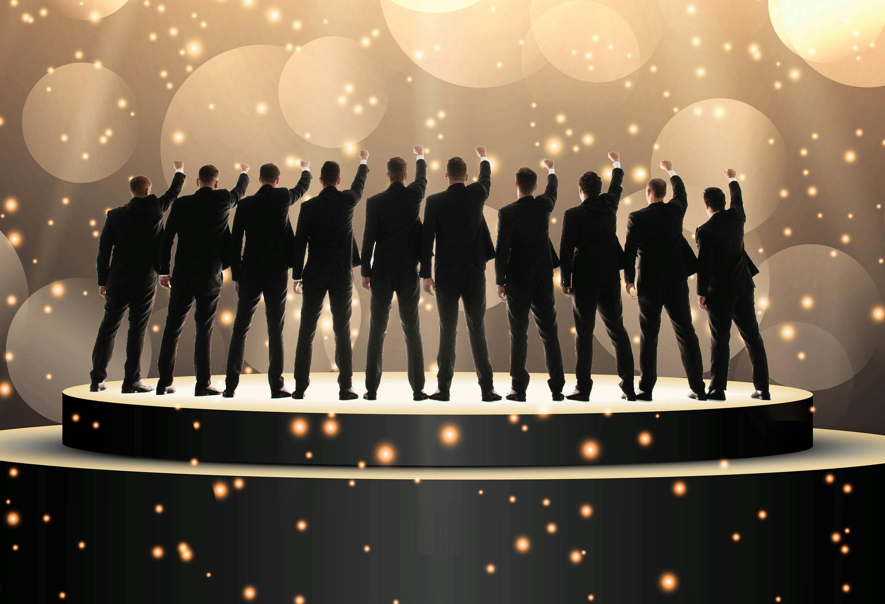 The TEN Tenors group pointing upwards on a stage.