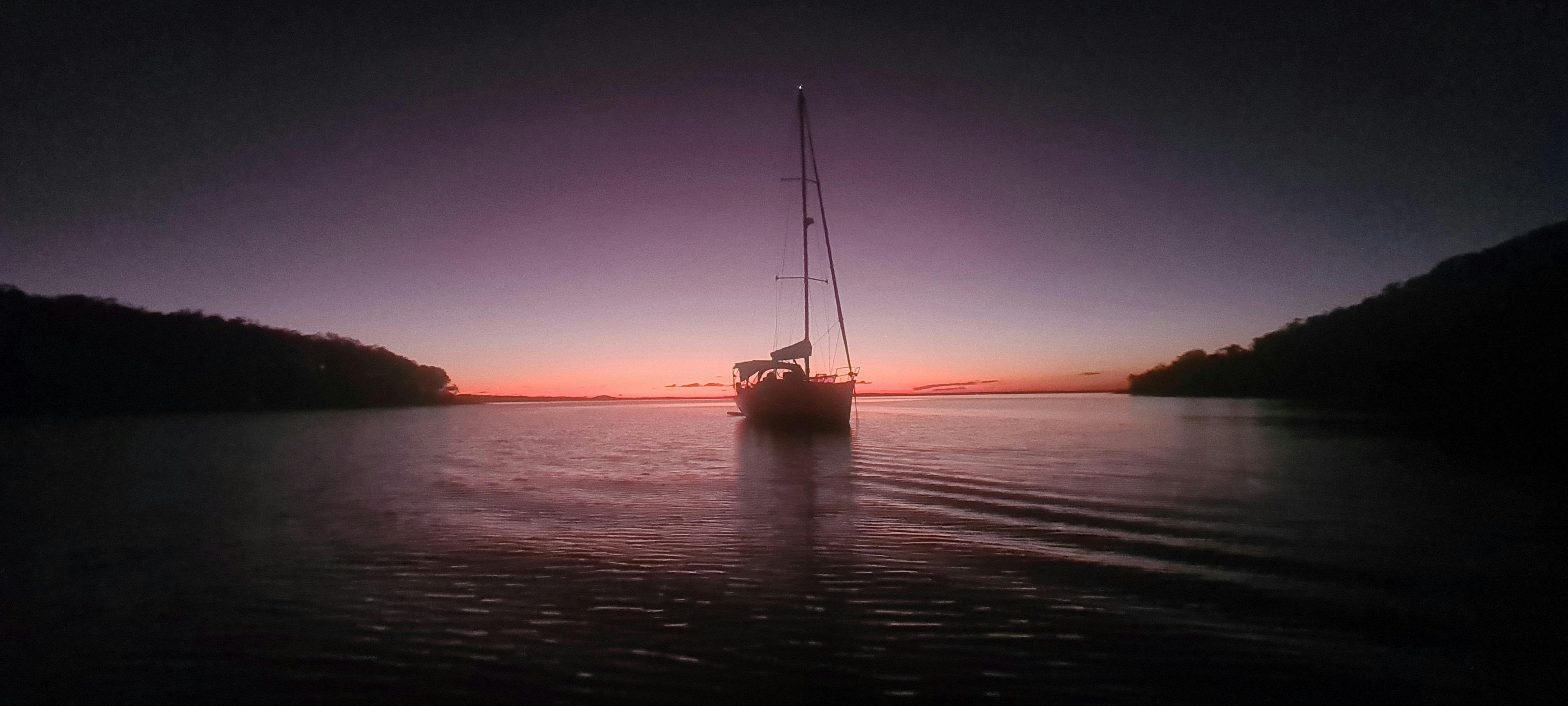 Watching a yacht as pink haze illuminates the water at sunset