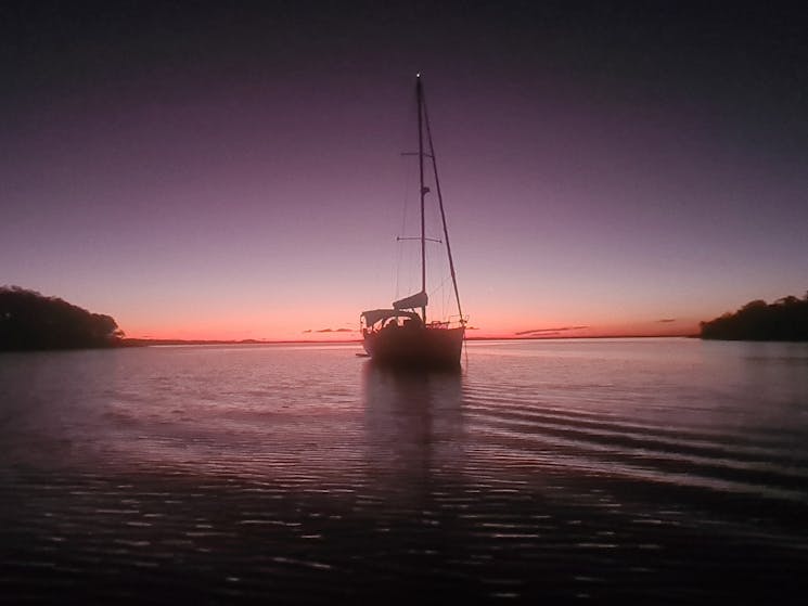 Watching a yacht as pink haze illuminates the water at sunset
