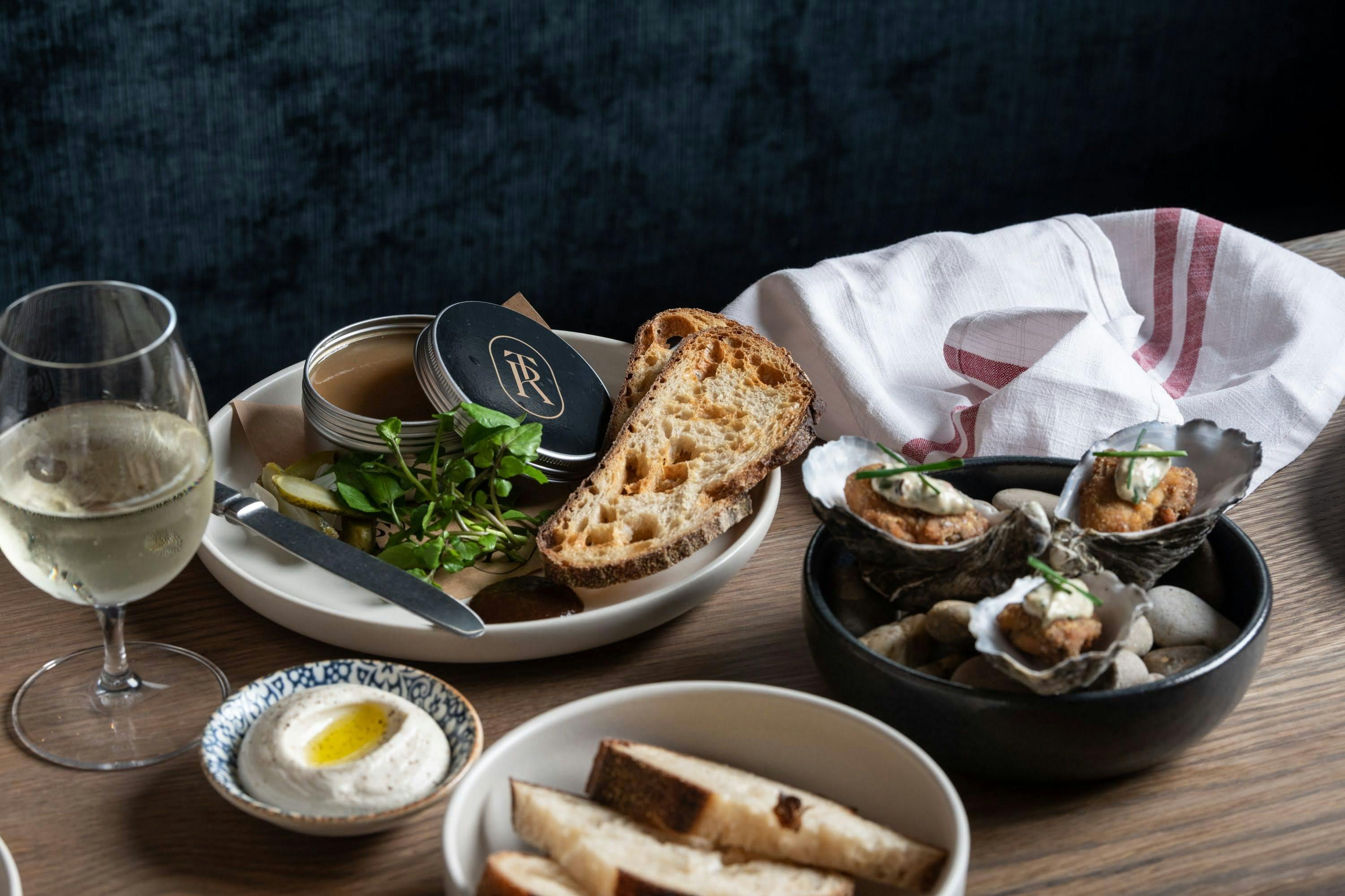 shows an example of dishes to eat at The Rover, Hollywood Quarter. includes oysters, sourdough, wine