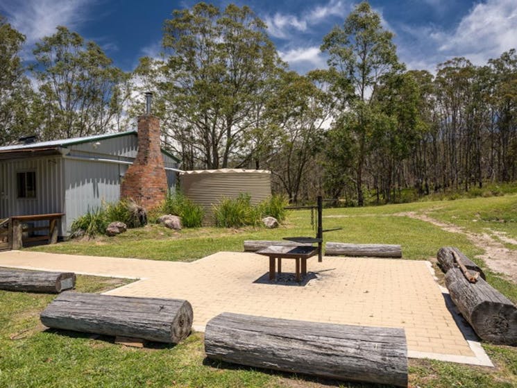The outdoor wood barbecue surrounded by log benches at Four Bull Hut in Washpool National Park.