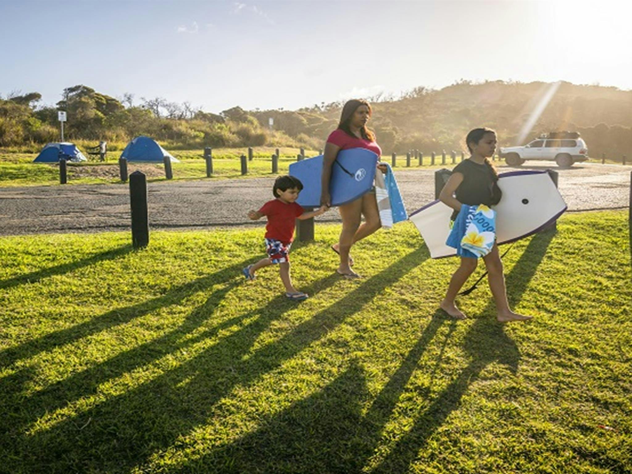 Eine Familie spaziert mit ihrer Badeausrüstung zum Frazer Beach auf dem Frazer-Campingplatz im Bundesstaat Munmorah.