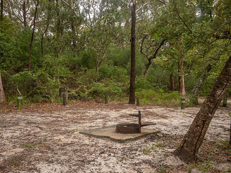View of sandy camping area with wood barbecue set in bushland. Photo: John Spencer &copy; DPIE