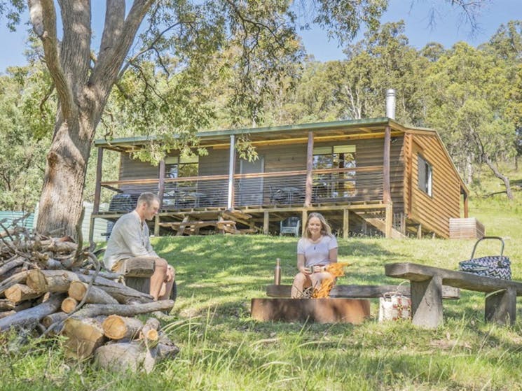A couple having a picnic at the fire pit outside Galong cabins in the Southern Blue Mountains area