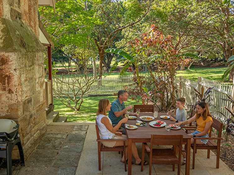 A family eating lunch in the courtyard of Gardeners Cottage in Sydney Harbour National Park. Photo: