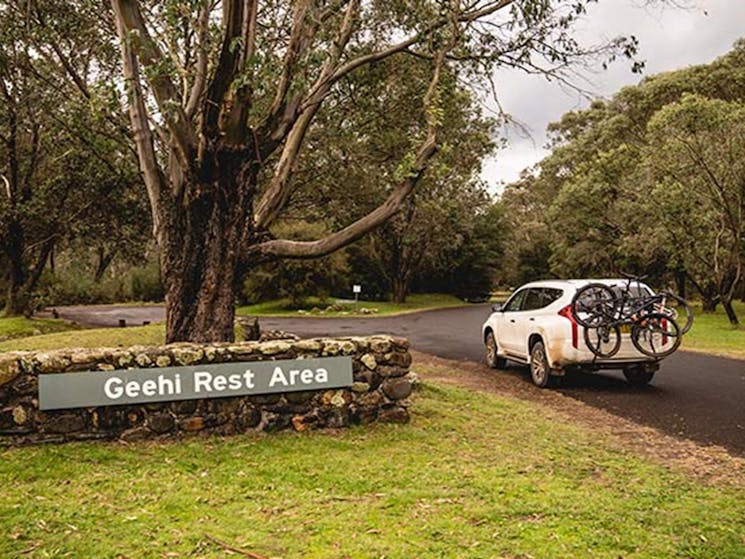 A car with bike rack passes a sign at Geehi Flats picnic area and campground, Kosciuszko National