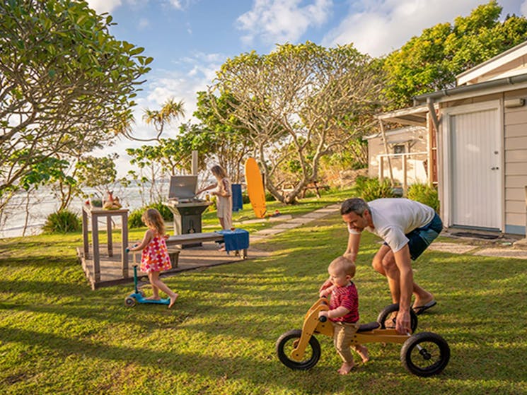 Family in the garden overlooking Byron Bay beach from Partridge Cottage. Photo: DPIE/John Spencer
