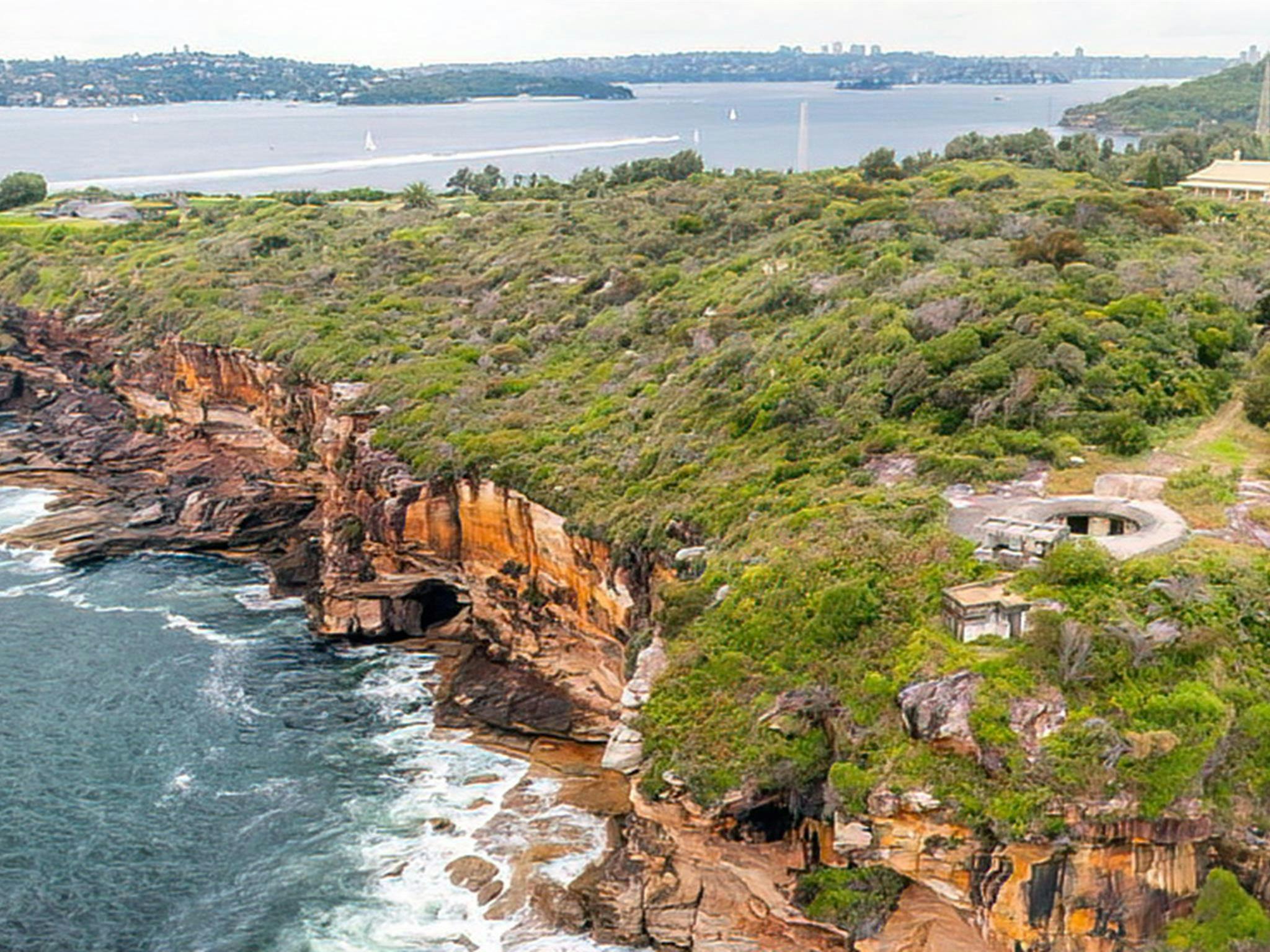 從空中俯瞰悉尼港國家公園的米德爾角，可以看到橙色的懸崖邊緣和大海。照片：