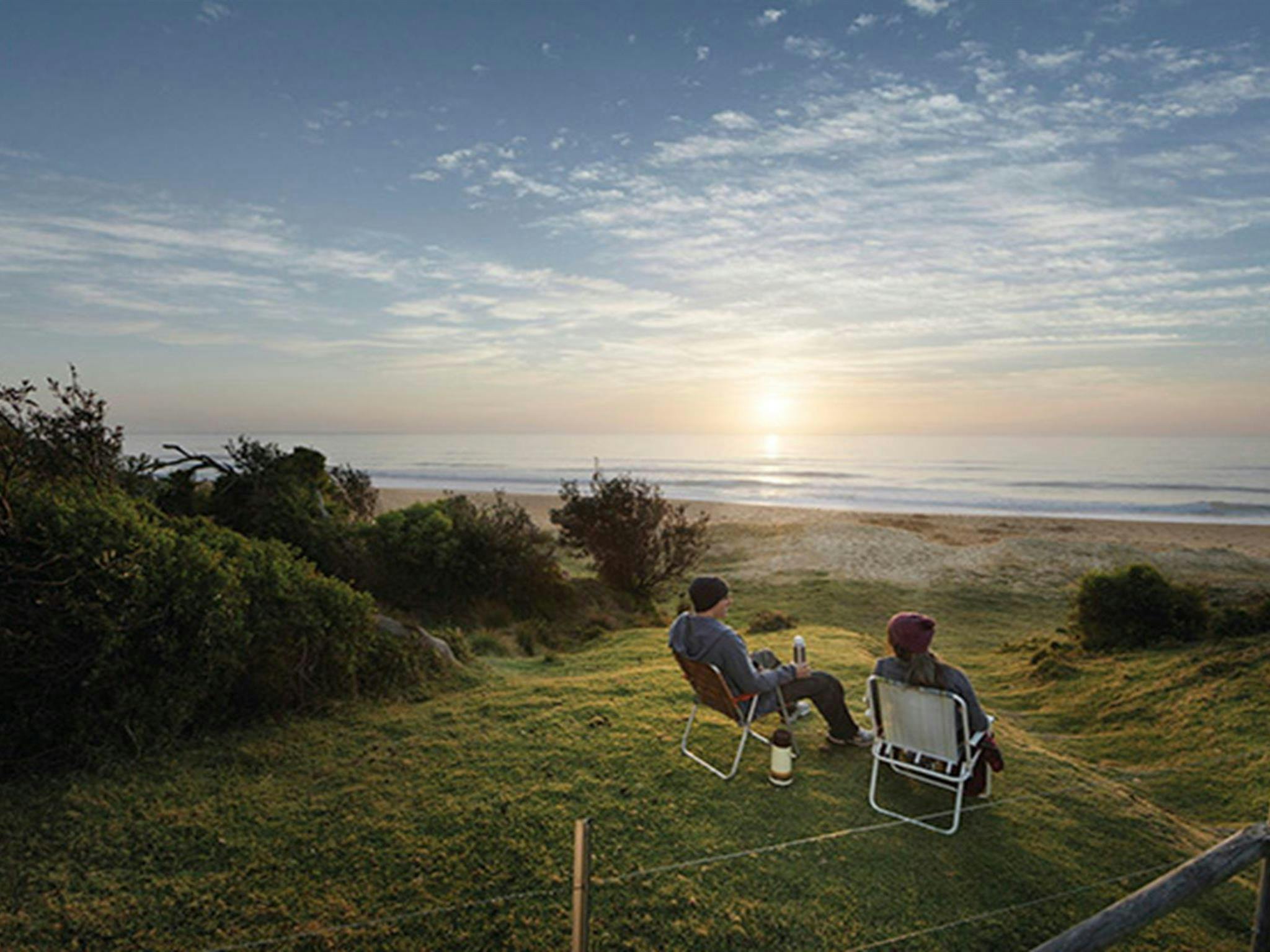 A couple watching the sunrise at Gillards campground, Mimosa Rocks National Park. Photo: David