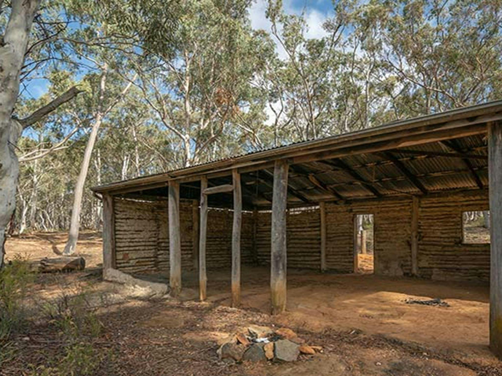 A large wooden shelter with a red dirt floor at Glendora campground in Hill End Historic Site.