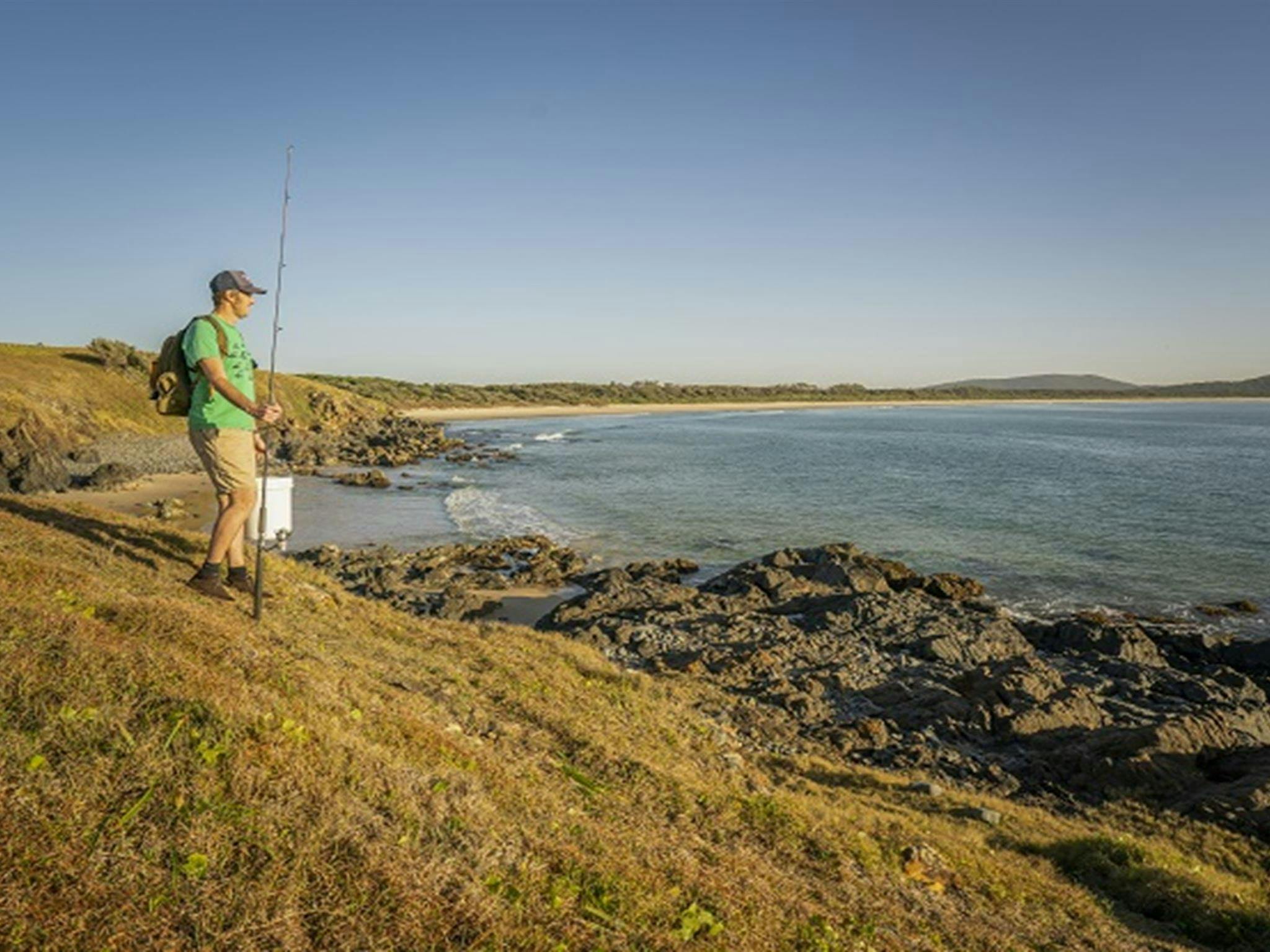 A fisherman walking along the coastline at Goolawah National Park. Photo: John Spencer/OEH