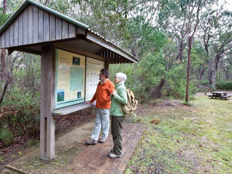 Two people looking at the interpretive signs at Granite picnic area in Washpool National Park.