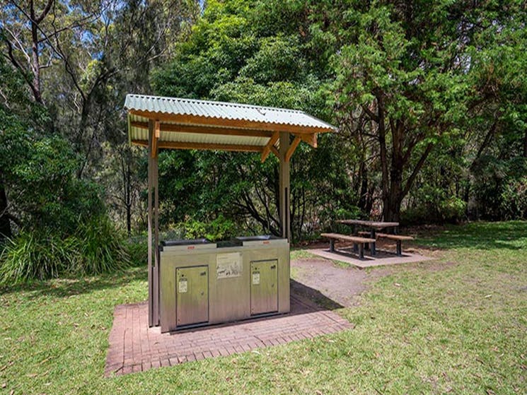 A covered barbecue with a picnic table in the background at Greenfield Beach picnic area in Jervis