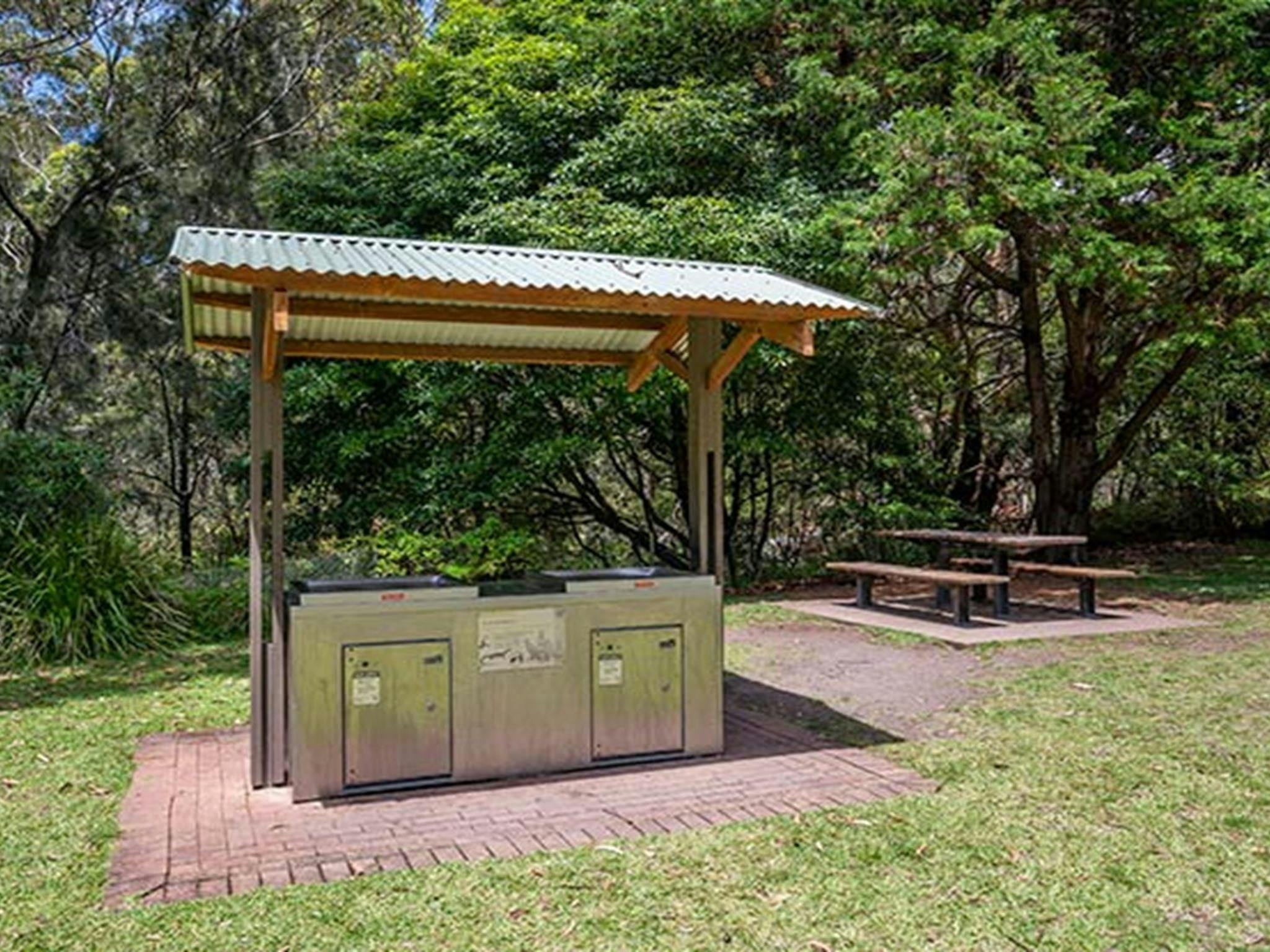 A covered barbecue with a picnic table in the background at Greenfield Beach picnic area in Jervis