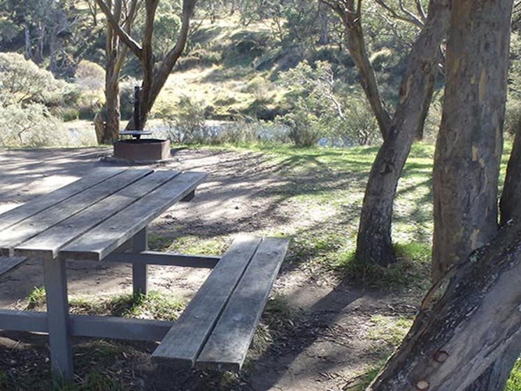 A timber picnic table at Gungarlin River, with a view of the river, Kosciuszko National Park. Photo: