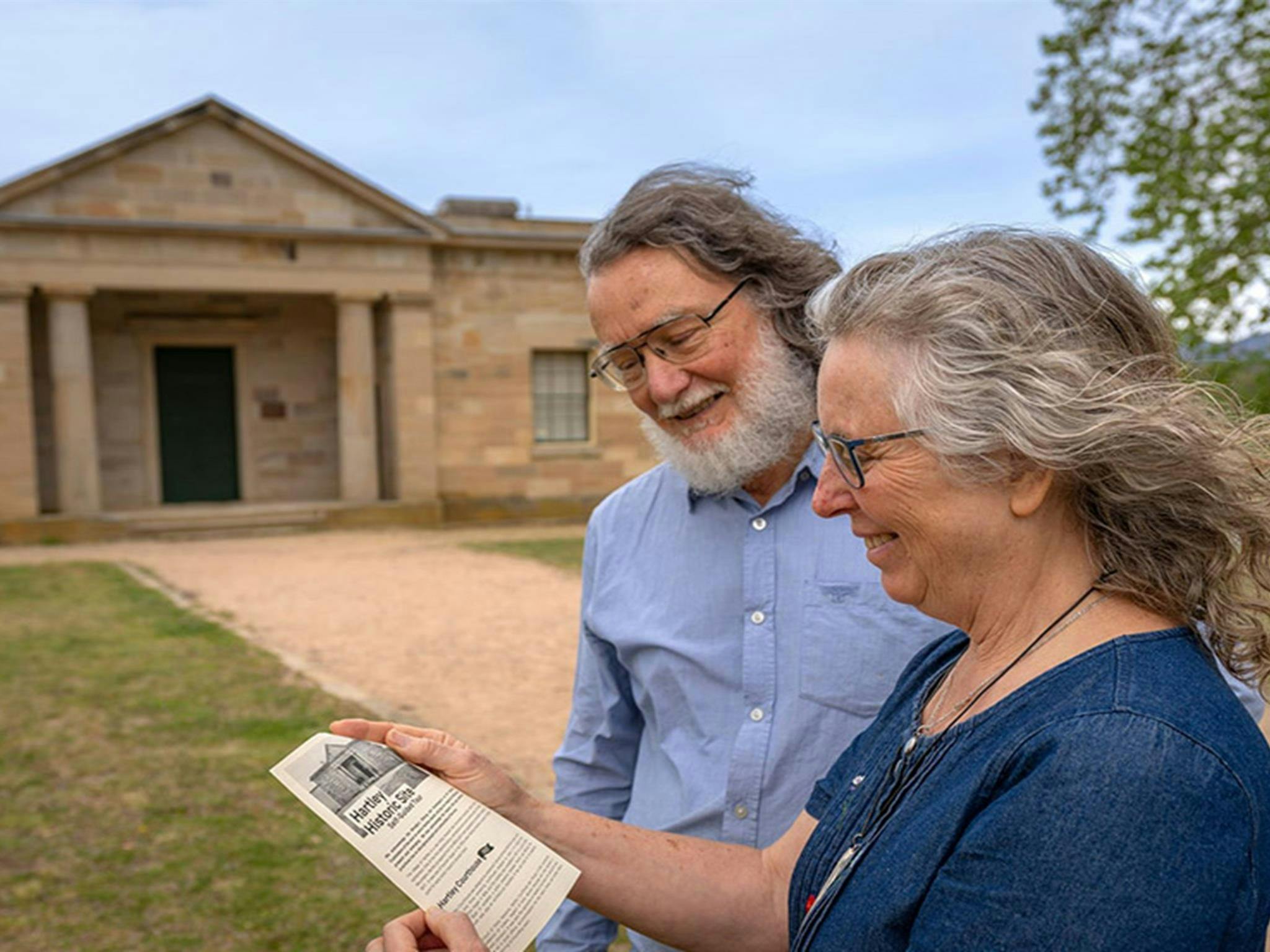 Zwei Personen lesen eine Broschüre vor dem Gerichtsgebäude in Hartley auf dem Gelände der historischen Stätte Hartley. Foto: John
