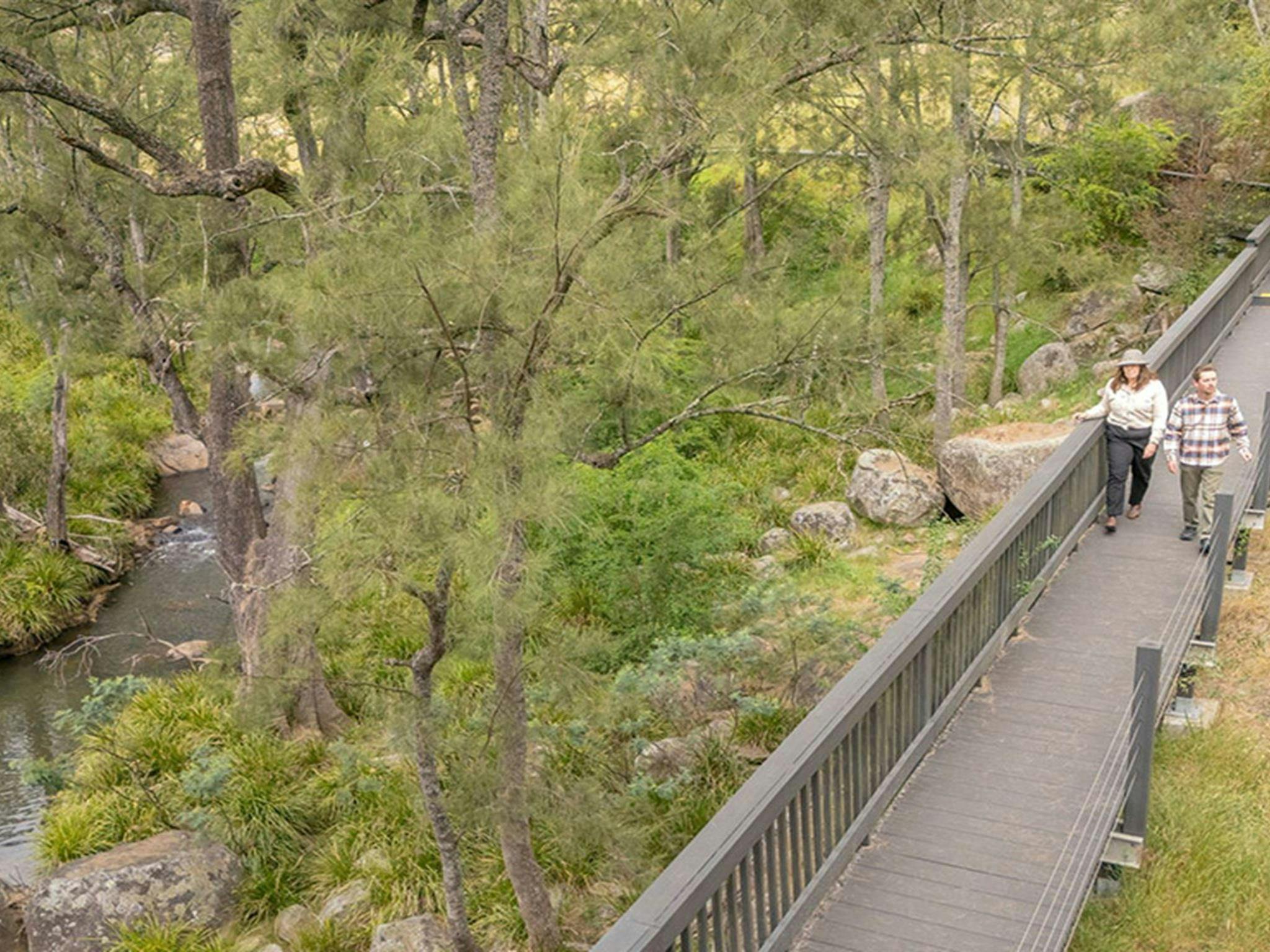 2 people on Rowsons River walk, a boardwalk surrounded by bush next to the River Lett near Hartley