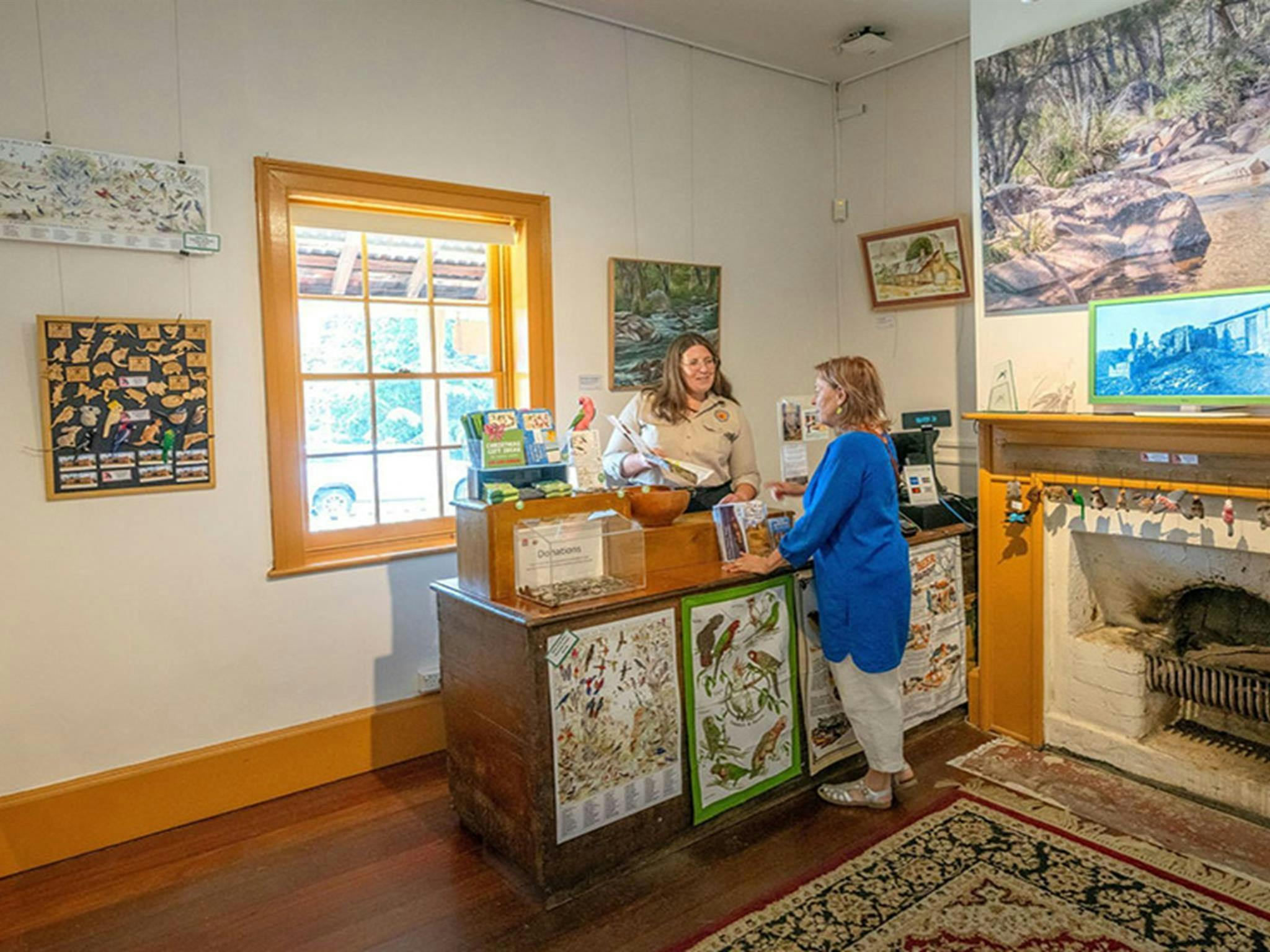 A visitor talking to a Hartley Historic Site Visitor Centre staff member at the counter beside an