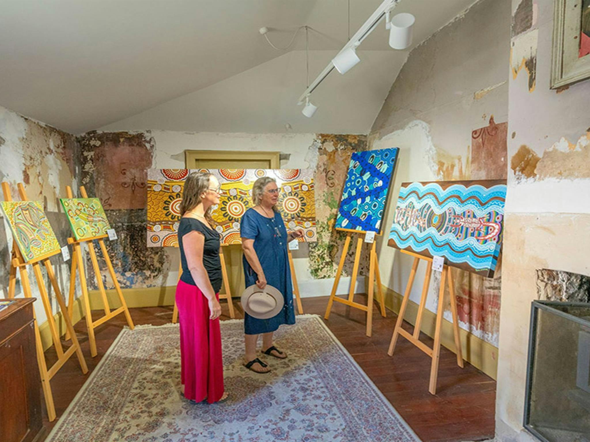 Visitors looking at Aboriginal paintings on display inside Hartley Historic Site Visitor Centre.