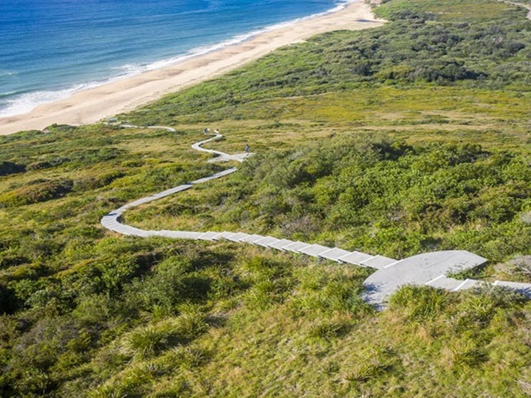Aerial view of walking track through bushland to a pristine beach near Hickson Street lookout.