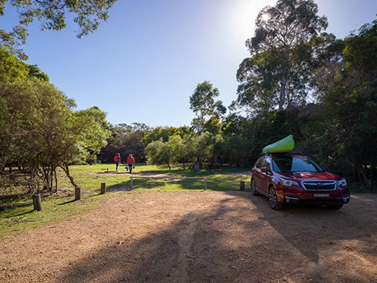 Two people walking away from a car parked at Hobart Beach campground, Bournda National Park. Photo: