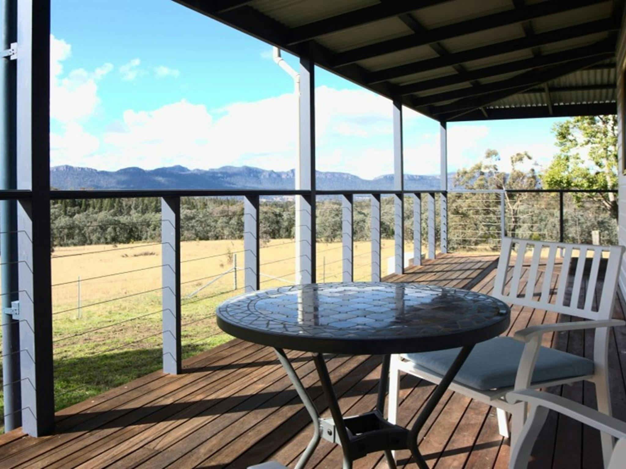Die umlaufende Veranda mit Tisch und Stühlen im Honeyeater Homestead mit Blick auf Capertee