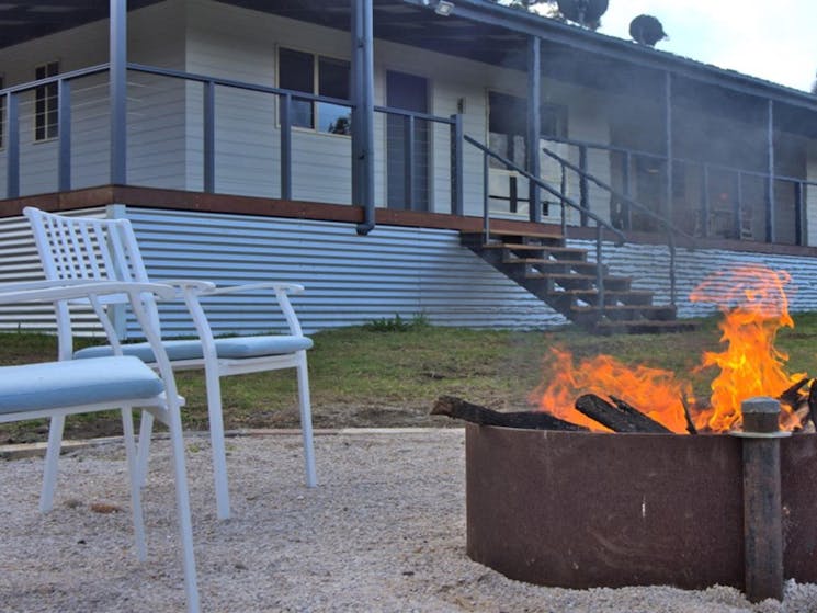 An outdoor firepit and chairs with Honeyeater Homestead in the background, in Capertee National Park