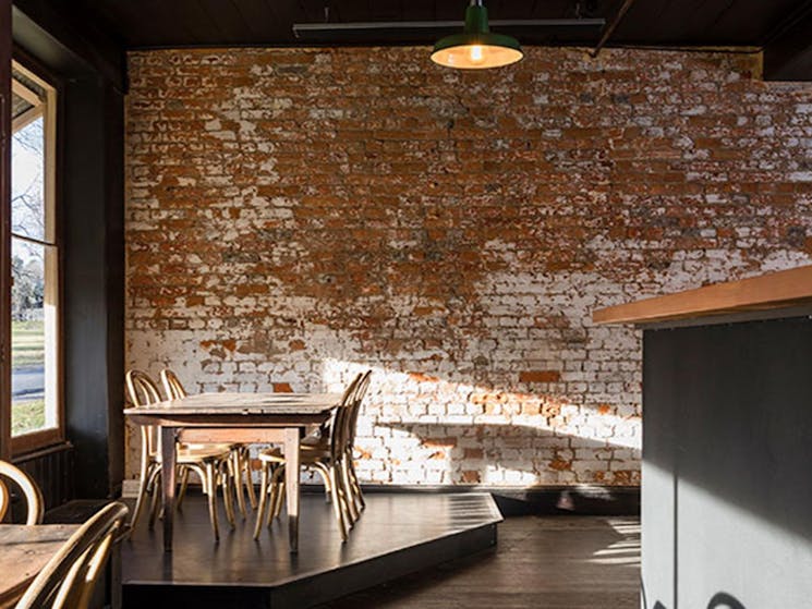 Tables and chairs next to the window with an exposed brick wall in the background at Hosies in Hill