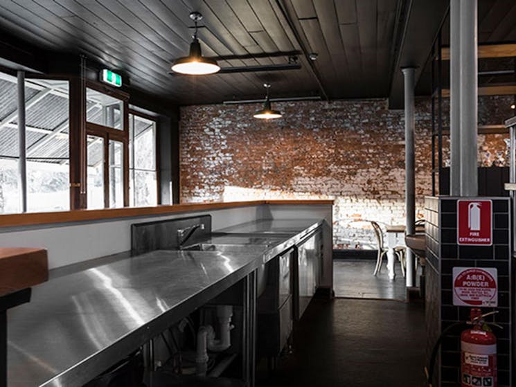 The benchtop in the commercial kitchen with a view towards the windows and tables at Hosies. Photo: 