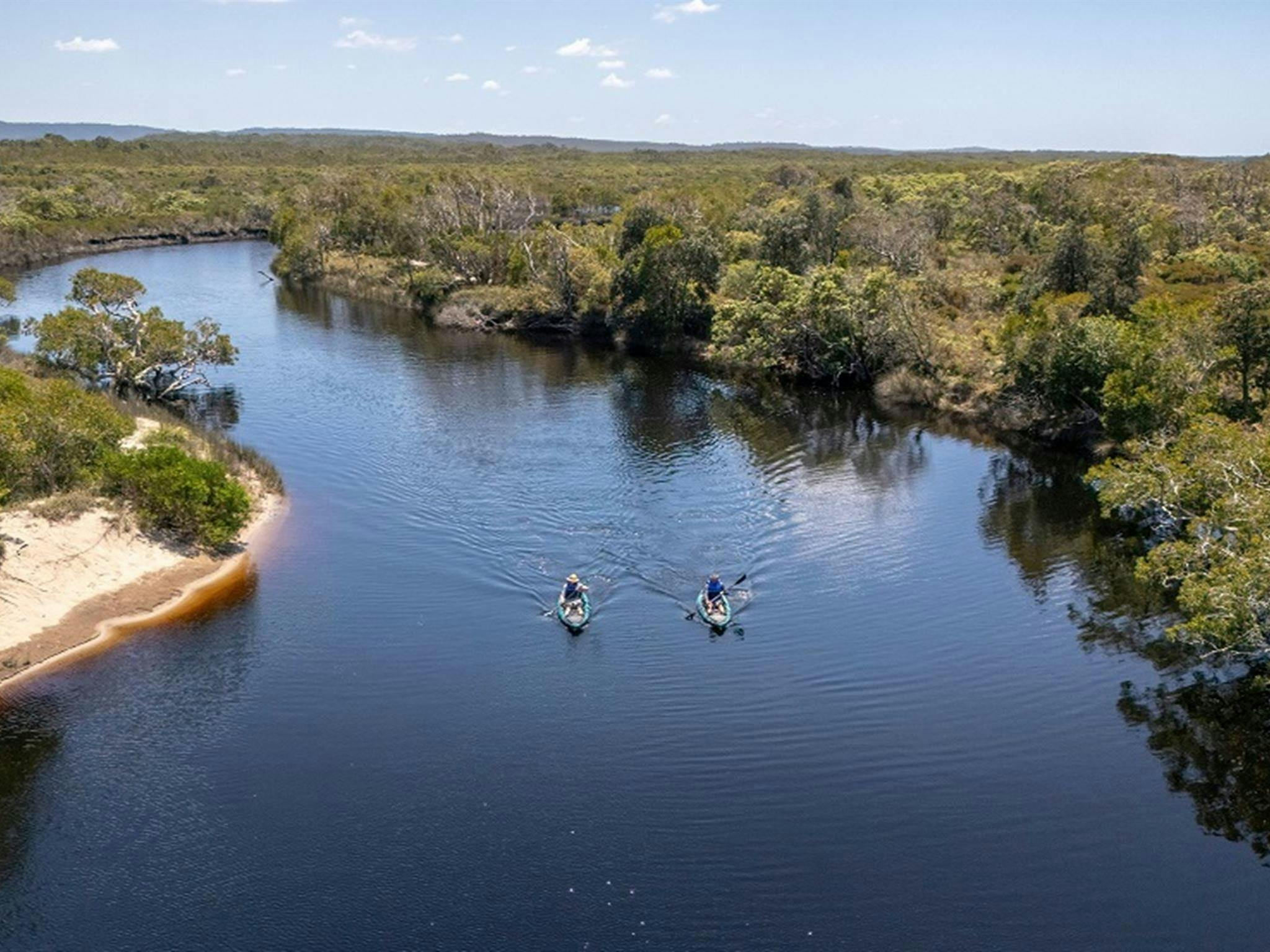 Aerial view of paddlers in a wider section of Jerusalem Creek, with the sky reflected in the water,