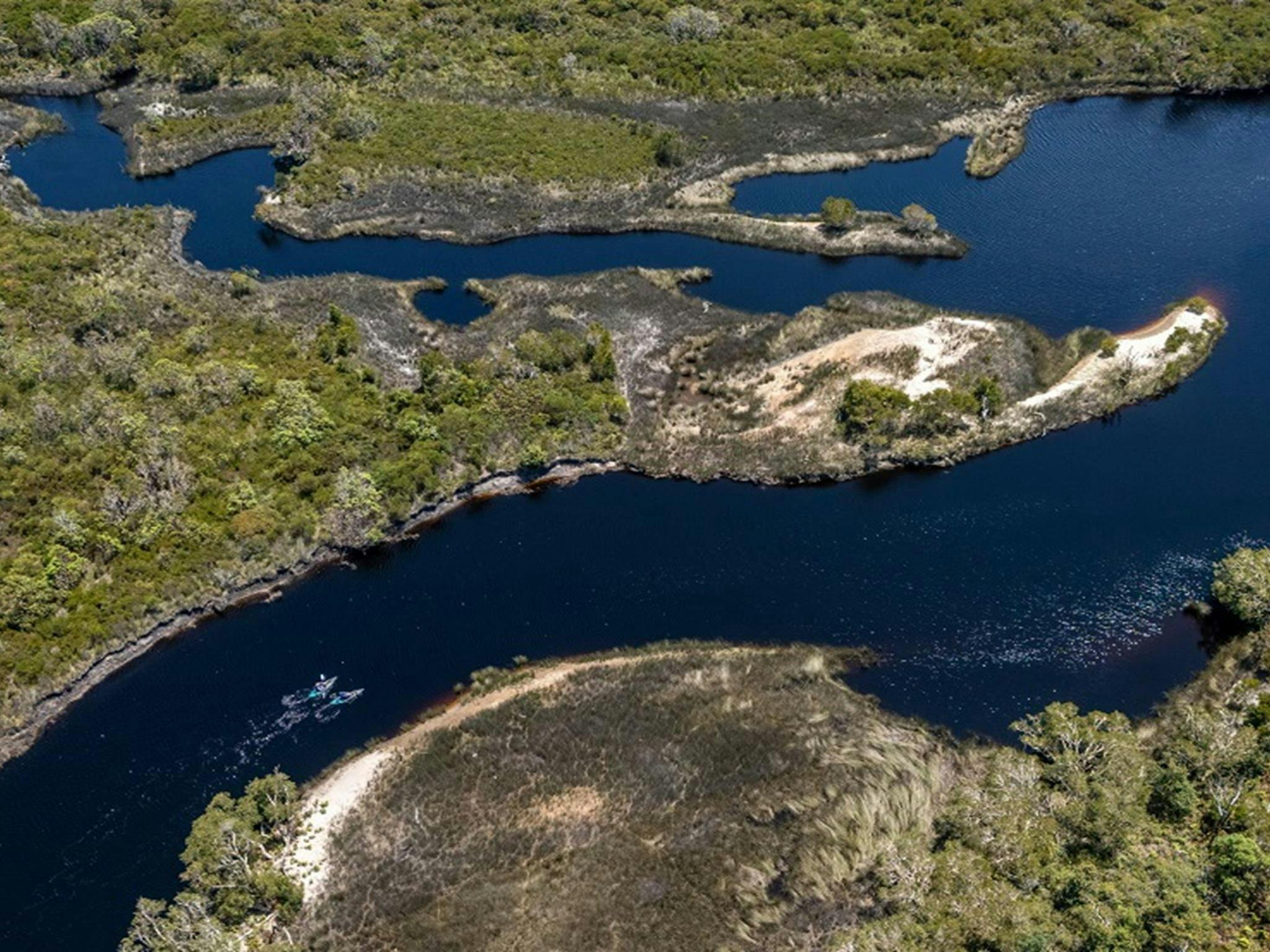 A wider aerial view of Jerusalem Creek, showing distant paddlers and the curves of the creek with a