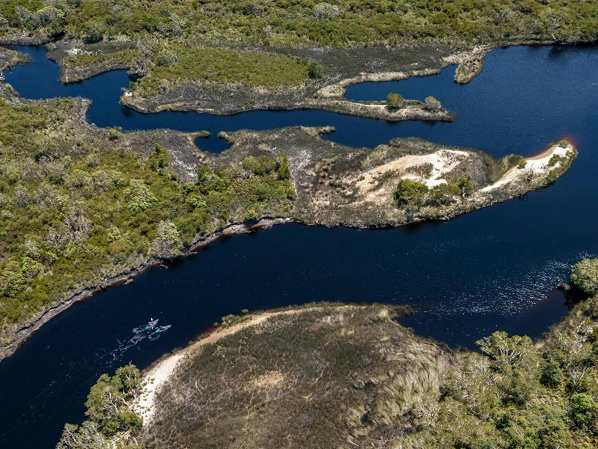 A wider aerial view of Jerusalem Creek, showing distant paddlers and the curves of the creek with a