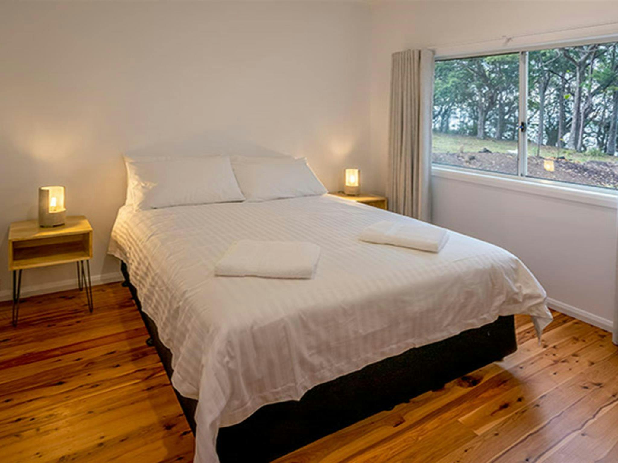 Judges House bedroom with queen bed and side wall window, Murramarang National Park. Photo: John