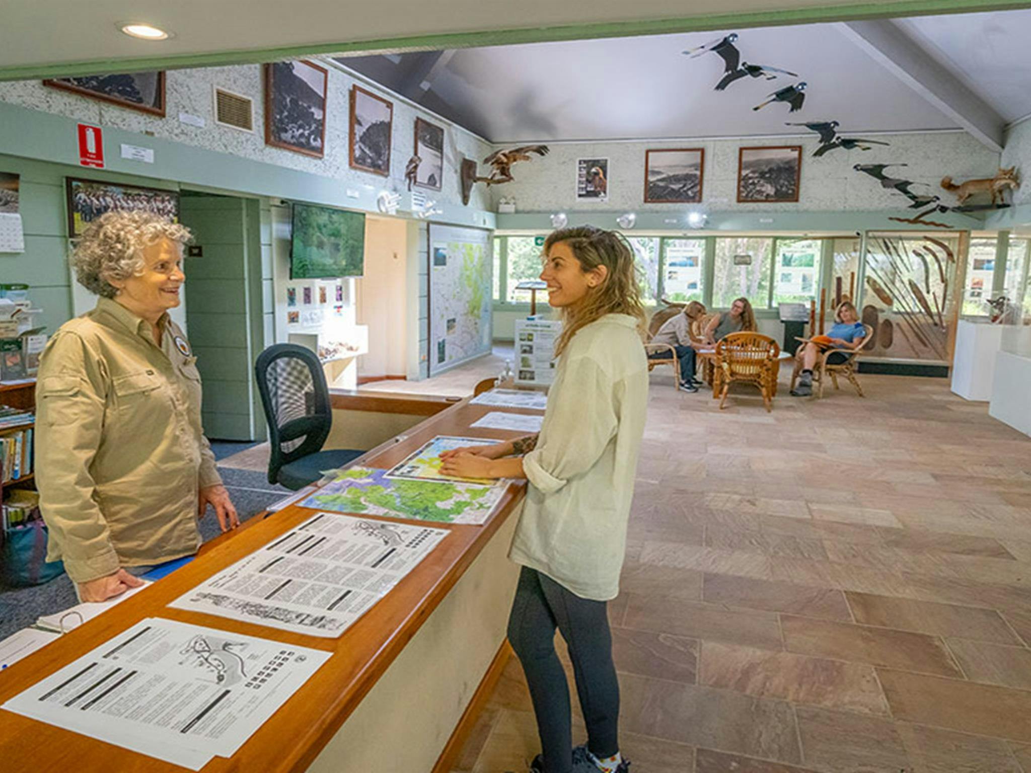 A visitor stands at the info desk talking to a volunteer at Kalkari Discovery Centre, Ku-ring-gai