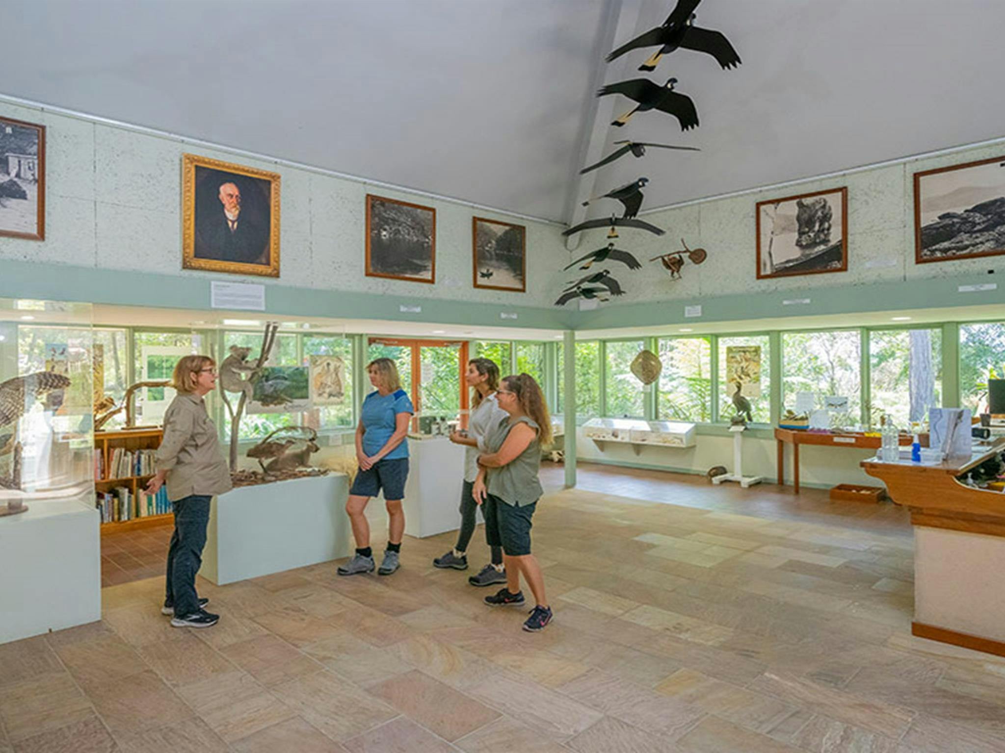 Three visitors listen to a volunteer to learn more about exhibits at the Kalkari Discovery Centre in