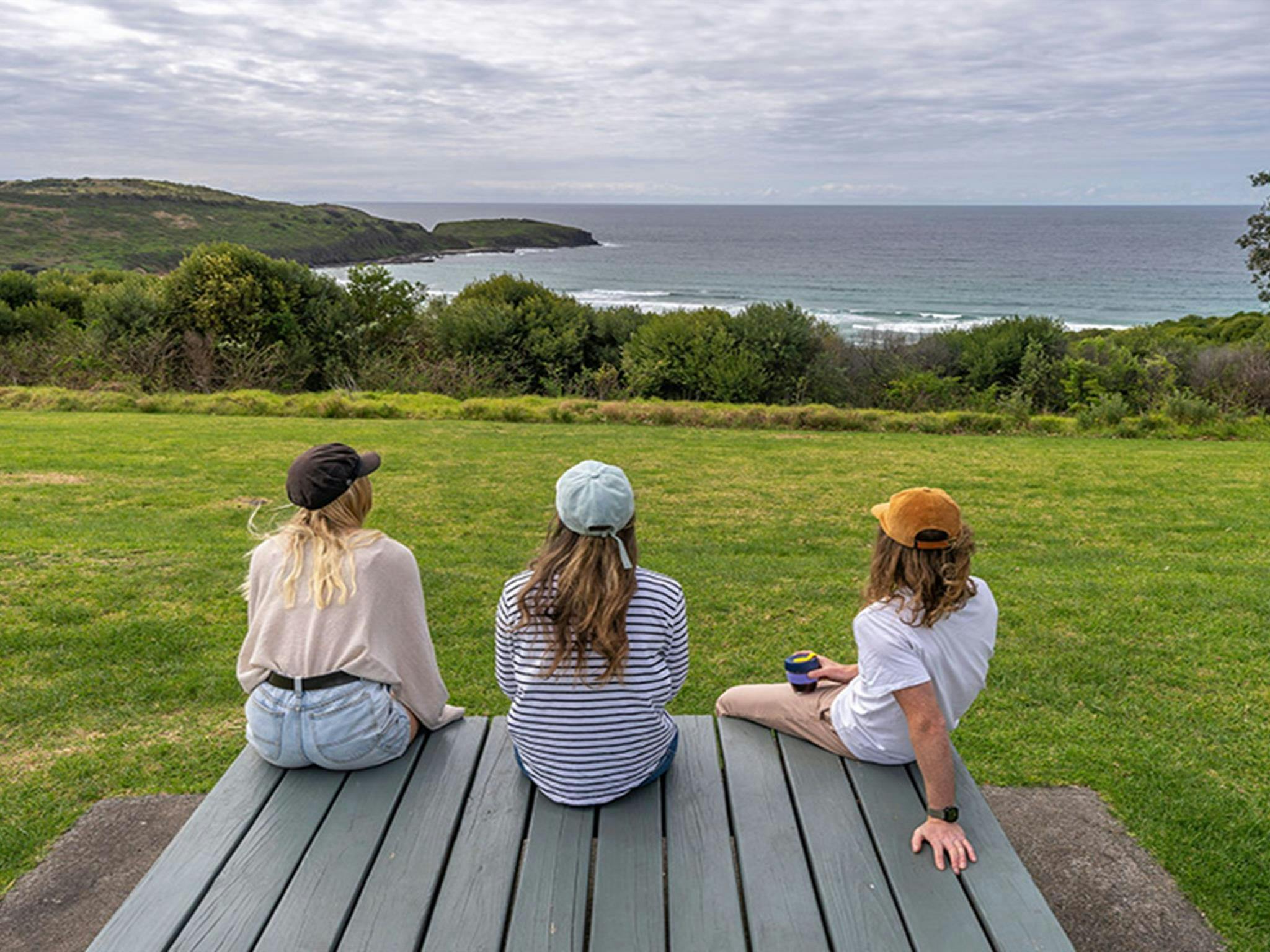 Visitors enjoying ocean views from the grassy area in Killalea Regional Park. Photo: John